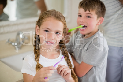 Siblings brushing teeth in bathroom