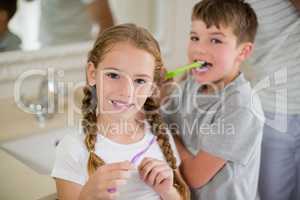 Siblings brushing teeth in bathroom