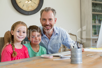 Happy father and kids sitting at desk