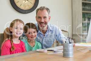 Happy father and kids sitting at desk