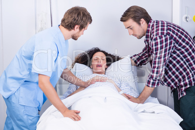 Doctor and man comforting pregnant woman in ward