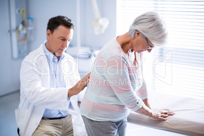 Physiotherapist giving back massage to senior patient