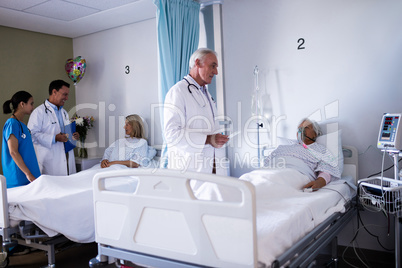 Male doctor interacting with senior patient in the ward