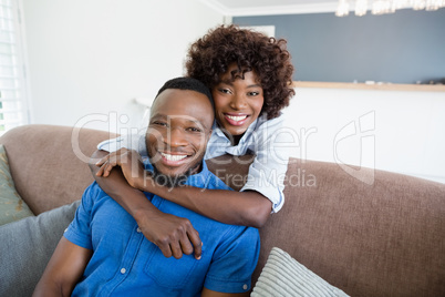 Happy couple embracing on sofa in living room at home