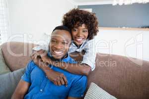 Happy couple embracing on sofa in living room at home