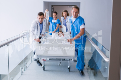 Doctors pushing emergency stretcher bed in corridor