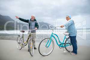 Senior couple standing with bicycles on the beach