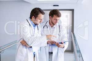 Doctors having discussion on clipboard in corridor