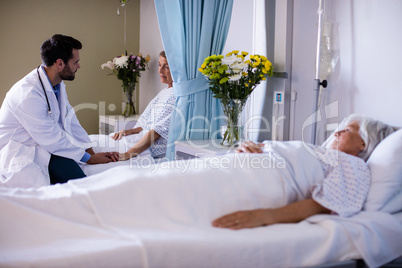 Male doctor consoling female senior patient