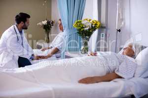 Male doctor consoling female senior patient