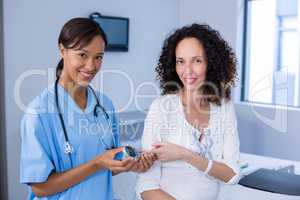 Portrait of doctor examining pregnant womans blood sugar
