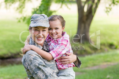 Portrait of happy female soldier with her daughter in park