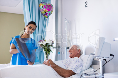 Female doctor discussing x-ray report with male senior patient in the ward