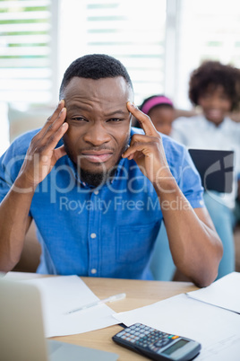 Worried man sitting at table with bills and laptop