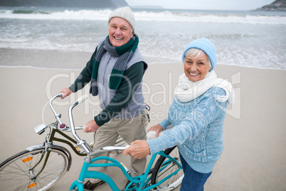 Portrait of senior couple standing with bicycles on the beach