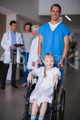 Doctor pushing disable girl in hospital corridor