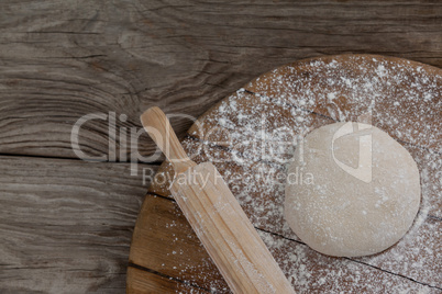Rolling pin with pizza dough and flour on rolling board