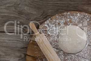 Rolling pin with pizza dough and flour on rolling board