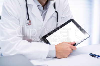 Mid section of male doctor holding digital tablet
