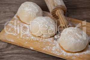 Rolling pin with pizza dough and flour on chopping board
