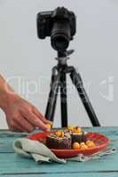Photographer keeping yellow cherry on dessert, camera in background