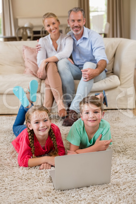 Portrait of sibling lying on rug while parents sitting in background