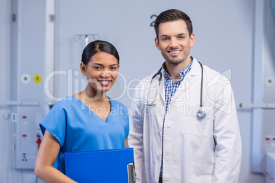 Portrait of smiling doctor and nurse standing with clipboard