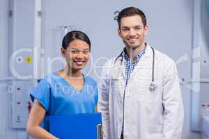 Portrait of smiling doctor and nurse standing with clipboard