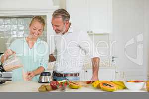 Smiling couple preparing fresh juice in kitchen
