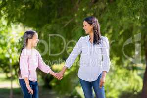 Mother holding hands of her daughter in park