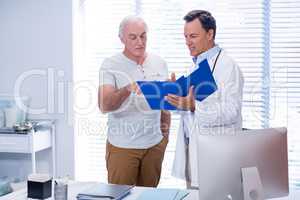 Doctor and senior man discussing on file