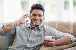 Man listening to music on mobile phone in living room at home