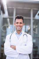 Portrait of smiling doctor standing with arms crossed