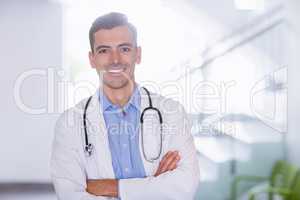 Portrait of smiling doctor standing with arms crossed
