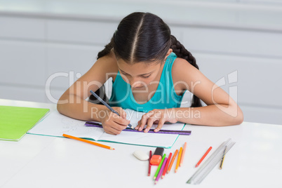 Attentive girl doing her homework in living room