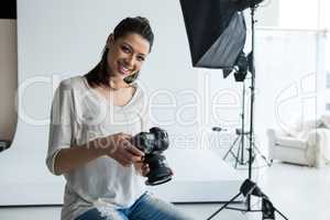 Portrait of female photographer holding digital camera