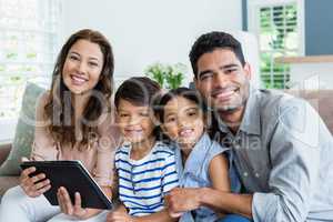 Parents and kids using digital tablet in living room at home