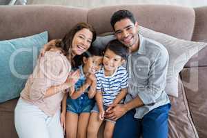 Portrait of happy parents and kids sitting on sofa in living room