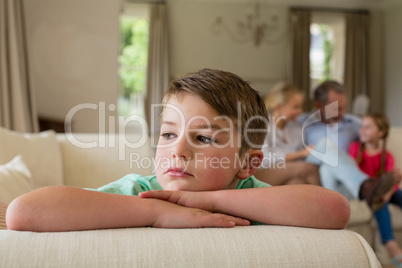 Thoughtful boy sitting on sofa in living room
