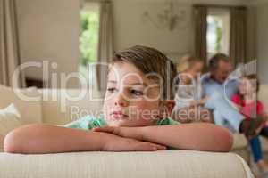 Thoughtful boy sitting on sofa in living room