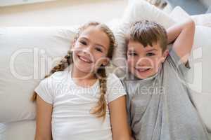 Siblings relaxing on bed in bedroom