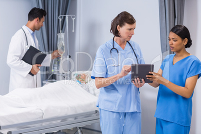 Doctor and nurse discussing over digital tablet