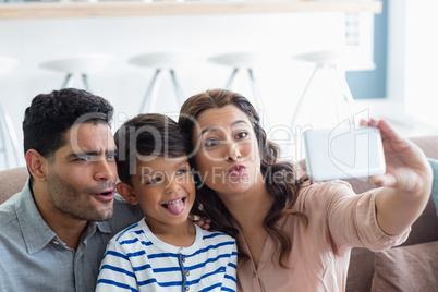 Parents and son taking a selfie from mobile phone in living room