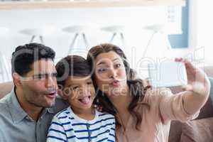 Parents and son taking a selfie from mobile phone in living room