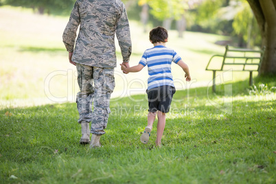 Army soldier walking with boy in park