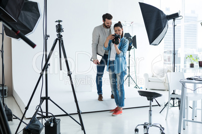 Photographer and male model reviewing captured photos in digital camera