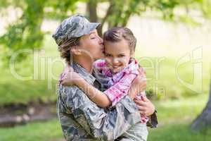 Happy female soldier kissing her daughter in park
