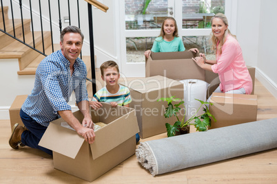 Parents and kids unpacking carton boxes in living room