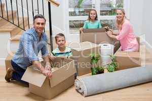 Parents and kids unpacking carton boxes in living room