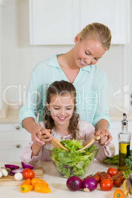 Mother and daughter preparing salad in kitchen at home